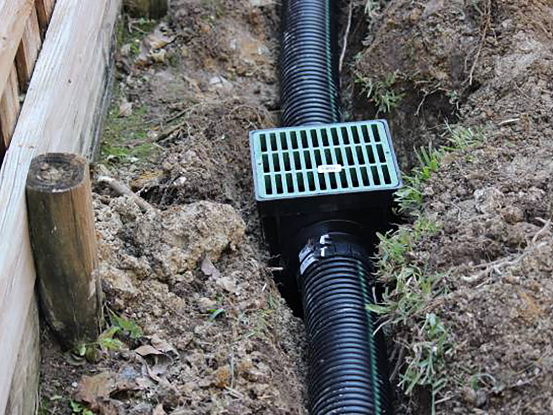 Commercial landscaping service drainage ditch. Laying a drainage pipe using rain drainage sewage pipe and box. Earthwork.